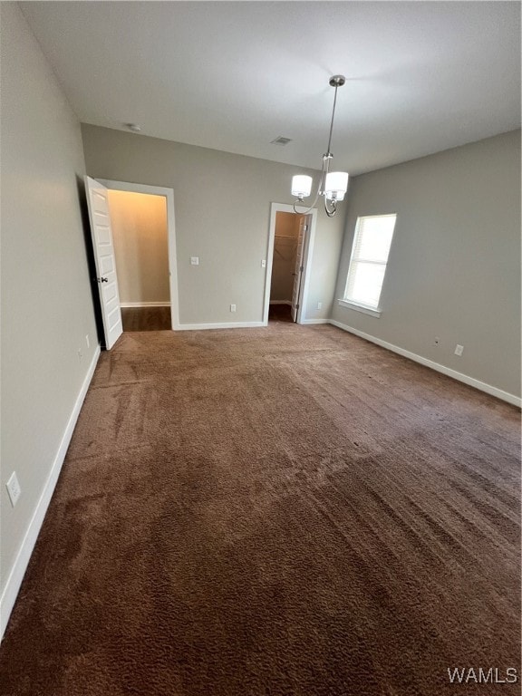 carpeted empty room with an inviting chandelier