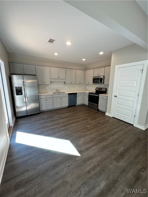 kitchen with appliances with stainless steel finishes, dark hardwood / wood-style flooring, gray cabinetry, and sink