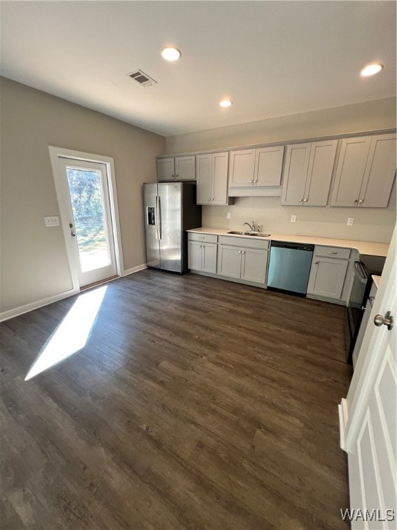 kitchen with appliances with stainless steel finishes, gray cabinets, dark wood-type flooring, and sink