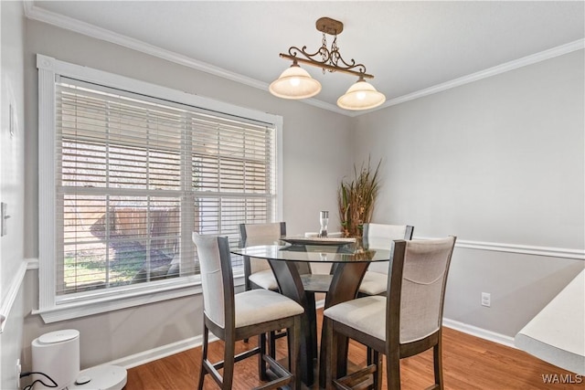 dining space with crown molding, baseboards, and wood finished floors