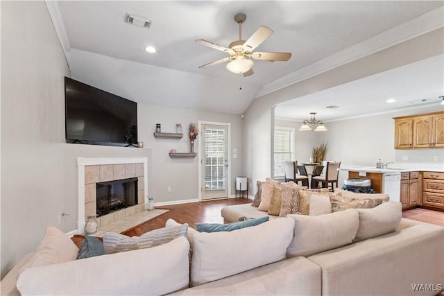 living room featuring baseboards, visible vents, a tile fireplace, light wood-style flooring, and crown molding