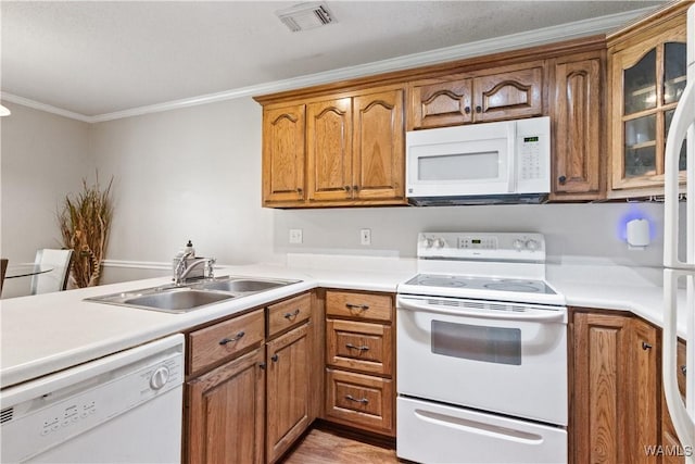 kitchen featuring white appliances, visible vents, brown cabinetry, ornamental molding, and a sink