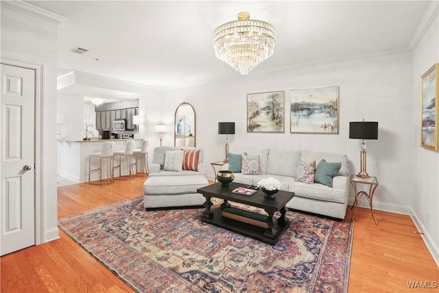 living room with crown molding, hardwood / wood-style flooring, and an inviting chandelier