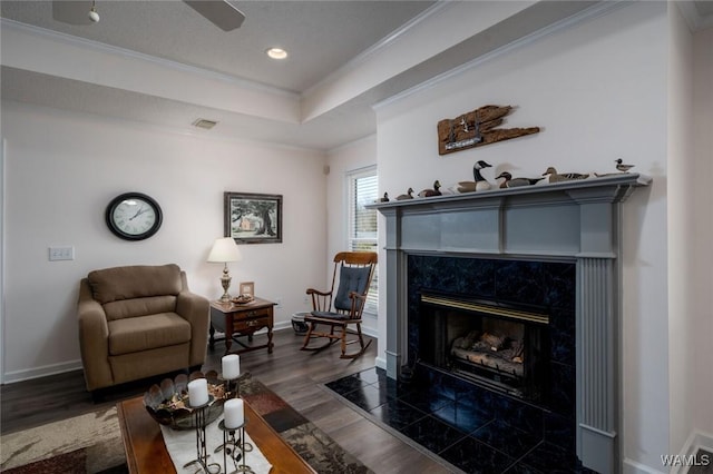 sitting room with ornamental molding, a tray ceiling, baseboards, and wood finished floors