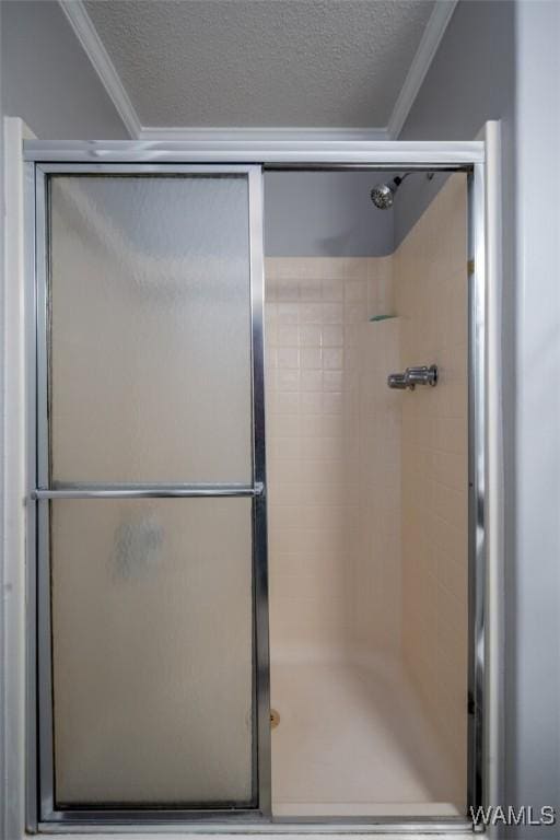 bathroom featuring a textured ceiling, ornamental molding, and a stall shower