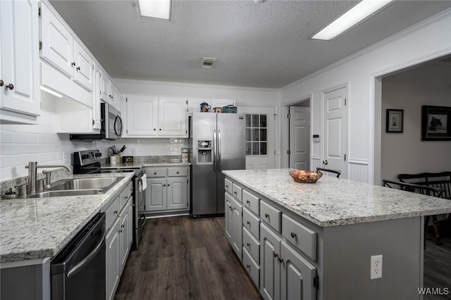 kitchen featuring gray cabinetry, stainless steel appliances, a sink, a center island, and dark wood finished floors