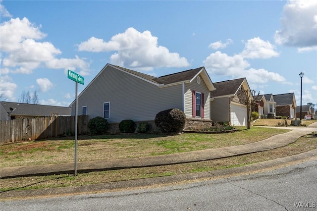 view of side of home featuring an attached garage, fence, a lawn, and brick siding