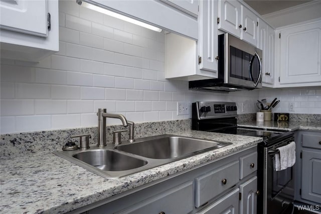 kitchen featuring stainless steel appliances, a sink, white cabinetry, gray cabinets, and backsplash