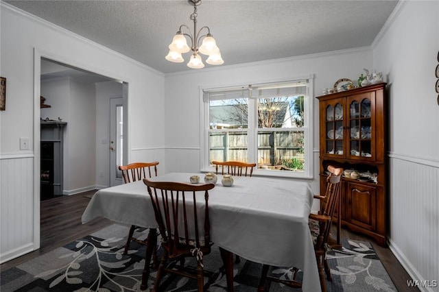 dining room with an inviting chandelier, a textured ceiling, wood finished floors, and wainscoting