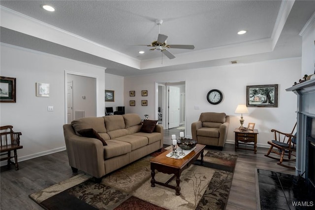 living area with ornamental molding, a tray ceiling, dark wood finished floors, and baseboards