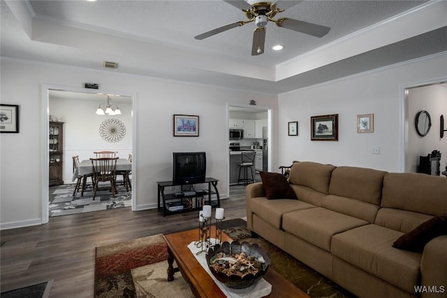 living room with visible vents, a tray ceiling, dark wood-style flooring, and ornamental molding