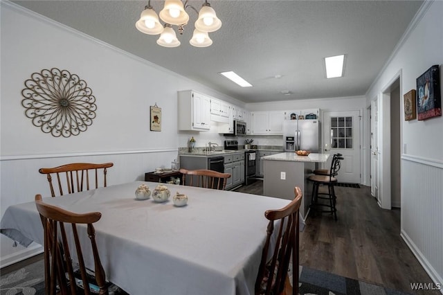 dining area featuring dark wood-style flooring, wainscoting, and a textured ceiling