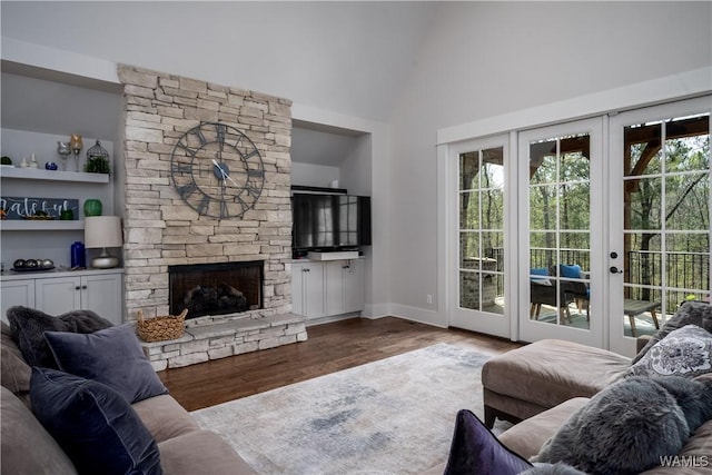 living room featuring wood finished floors, a fireplace, baseboards, high vaulted ceiling, and french doors
