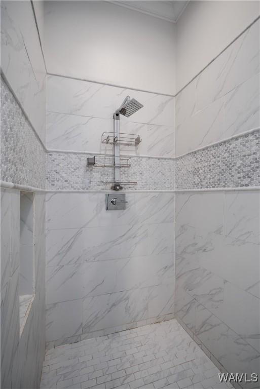 full bathroom featuring crown molding and tiled shower