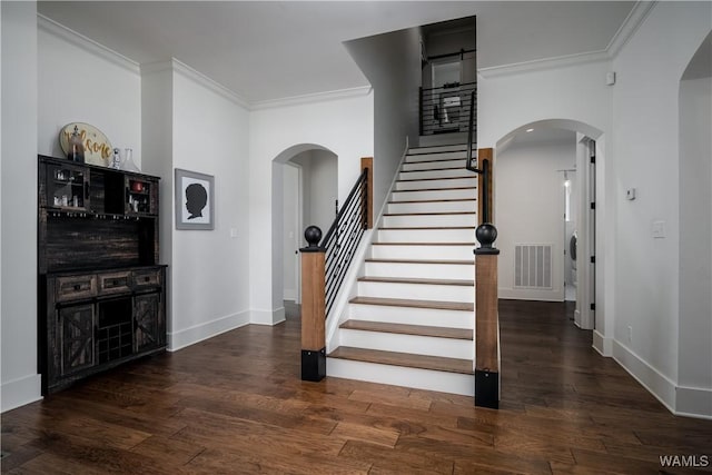 stairs featuring crown molding, arched walkways, visible vents, and wood finished floors