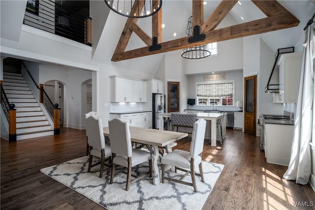 dining space featuring stairs, high vaulted ceiling, dark wood-style flooring, and arched walkways