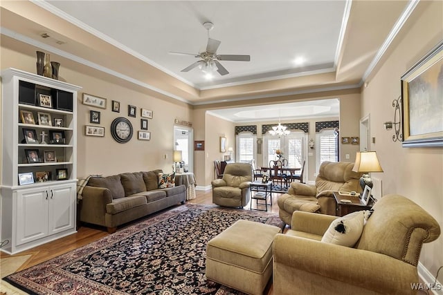 living room featuring ornamental molding, ceiling fan with notable chandelier, hardwood / wood-style floors, and a raised ceiling