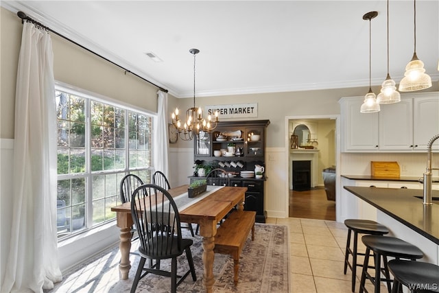 tiled dining space featuring plenty of natural light, crown molding, and an inviting chandelier