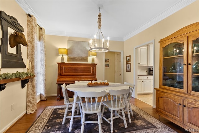 dining area featuring ornamental molding, a notable chandelier, and light wood-type flooring