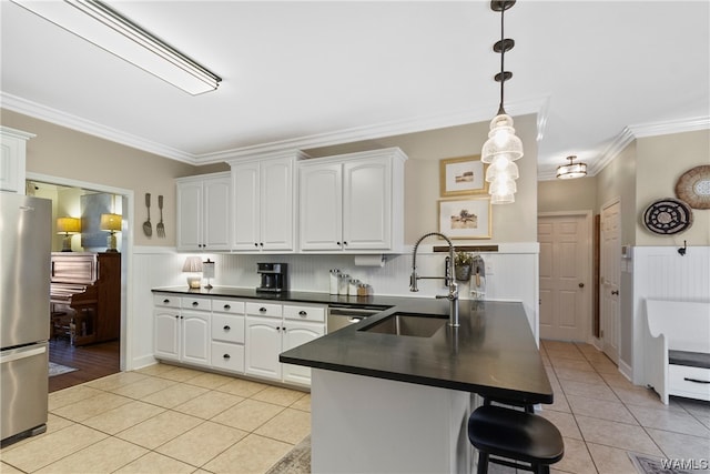 kitchen with kitchen peninsula, appliances with stainless steel finishes, crown molding, pendant lighting, and white cabinets