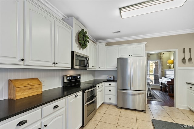 kitchen featuring white cabinets, stainless steel appliances, and ornamental molding