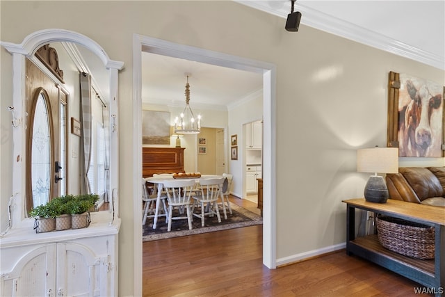 hallway with hardwood / wood-style floors, ornamental molding, and a notable chandelier