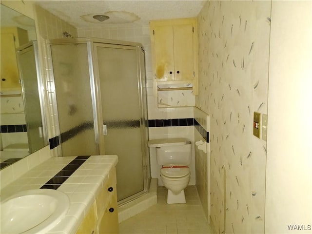 full bathroom featuring tile patterned flooring, a shower stall, vanity, toilet, and wallpapered walls