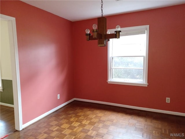 spare room with a chandelier and baseboards