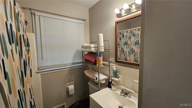 bathroom with backsplash, curtained shower, and sink