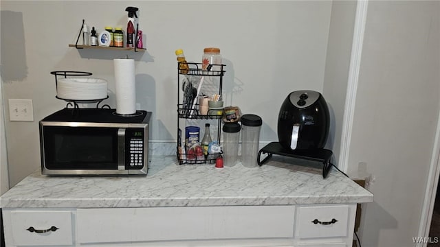 bar with white cabinetry and light stone countertops