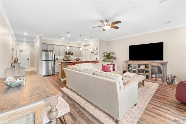 living room with ornamental molding, ceiling fan, and light hardwood / wood-style floors