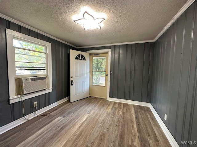 entrance foyer featuring a textured ceiling, cooling unit, crown molding, wood-type flooring, and wood walls