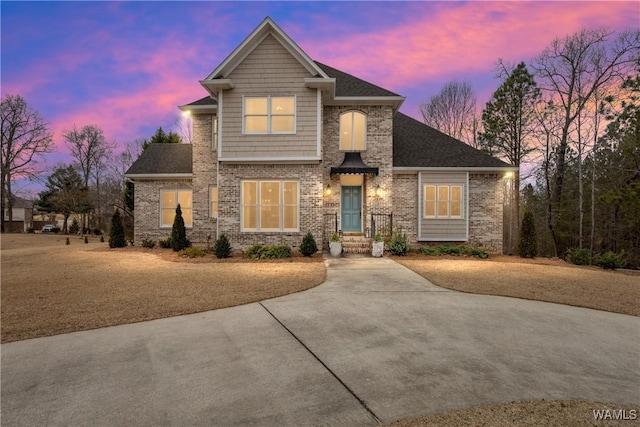 view of front of house featuring brick siding and roof with shingles