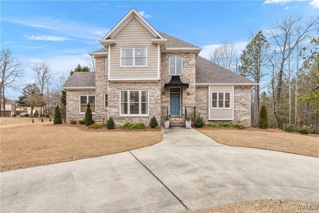 craftsman-style house featuring a front yard, brick siding, and roof with shingles