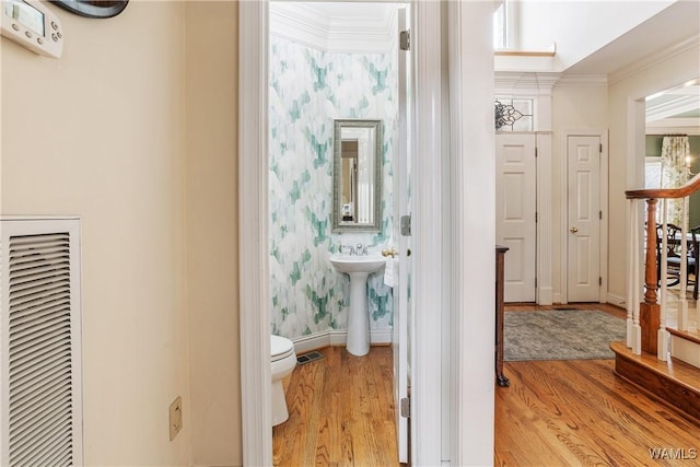 hallway with baseboards, ornamental molding, light wood finished floors, and wallpapered walls