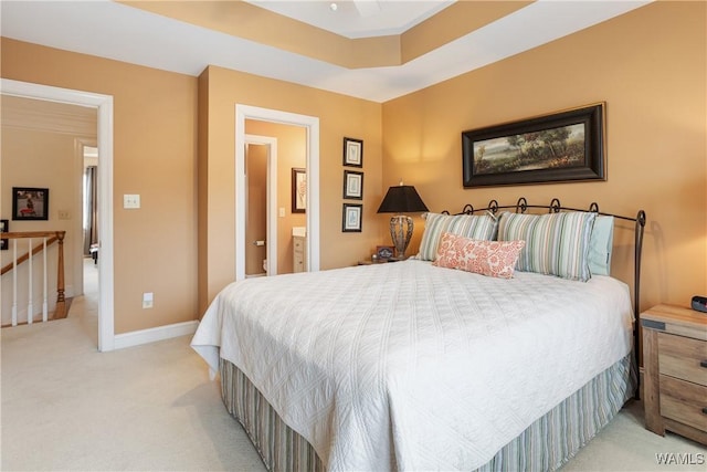 bedroom featuring light carpet, ensuite bath, and baseboards