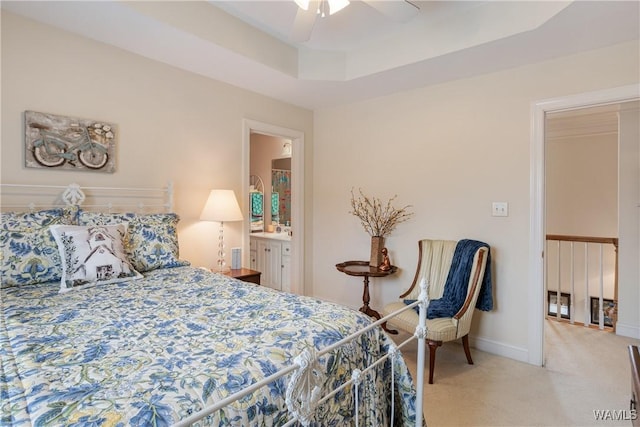 bedroom with ceiling fan, ensuite bath, carpet flooring, baseboards, and a raised ceiling