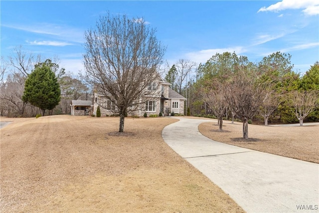 view of front of house with stone siding, a front lawn, and concrete driveway