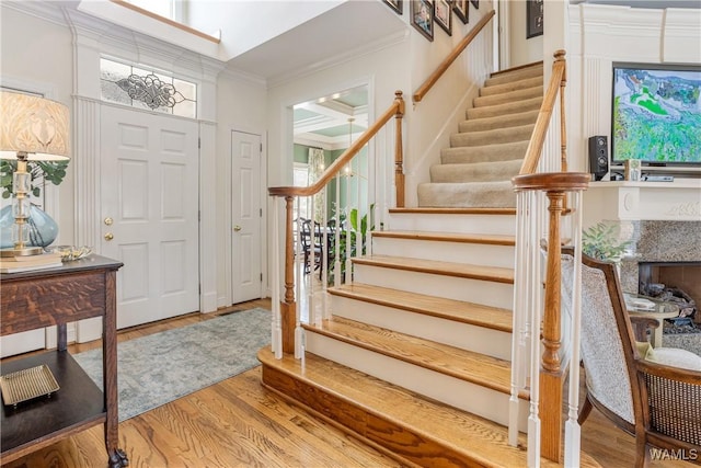 entryway with ornamental molding, stairway, and wood finished floors