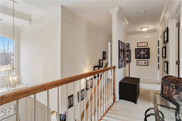 hallway featuring a notable chandelier, light colored carpet, ornamental molding, an upstairs landing, and baseboards