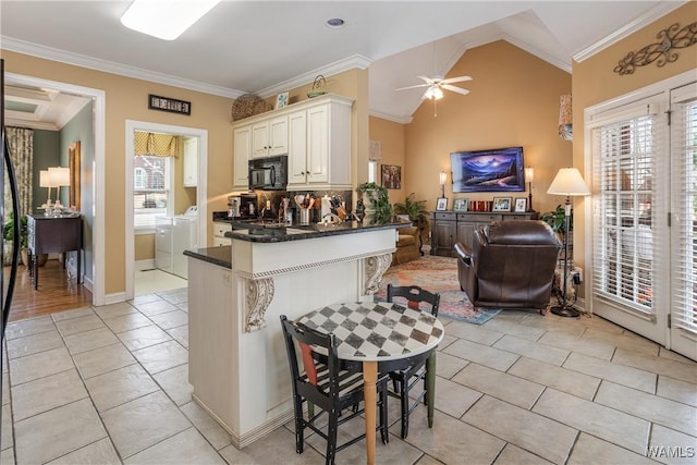 kitchen featuring a breakfast bar, black microwave, open floor plan, and crown molding