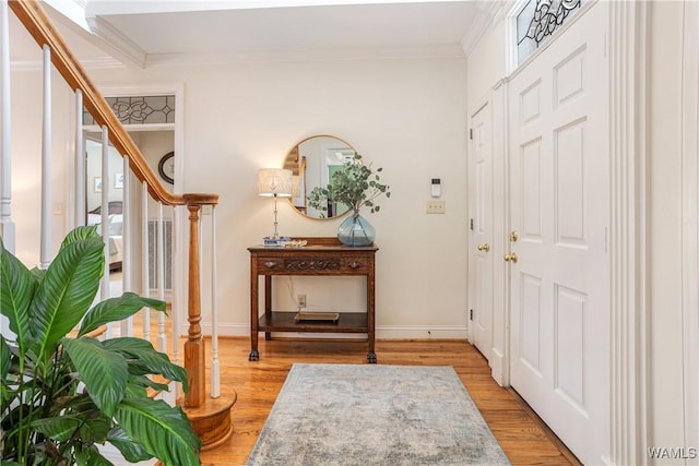 foyer with baseboards, stairway, light wood-type flooring, and crown molding