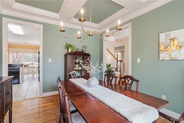 dining area featuring ornamental molding, a raised ceiling, light wood-style flooring, and baseboards