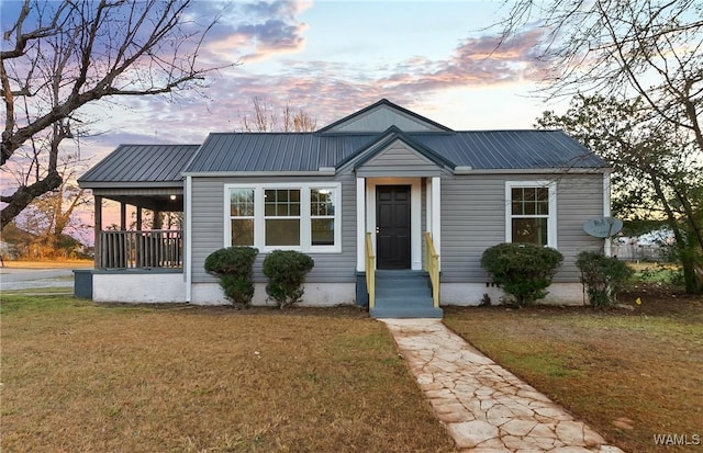 view of front of house featuring metal roof and a front lawn