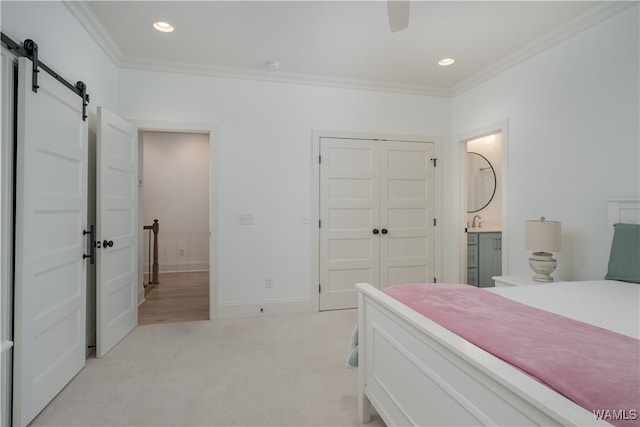 carpeted bedroom featuring connected bathroom, ceiling fan, a barn door, a closet, and ornamental molding