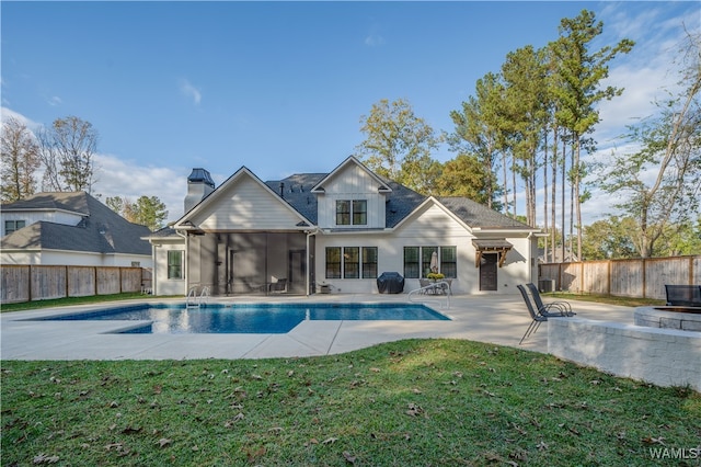 view of swimming pool with a sunroom, a patio area, and a lawn