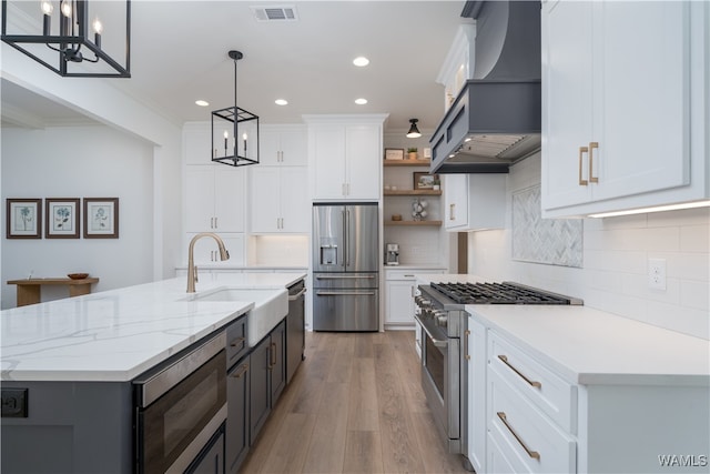 kitchen featuring white cabinets, decorative light fixtures, light hardwood / wood-style floors, custom range hood, and stainless steel appliances