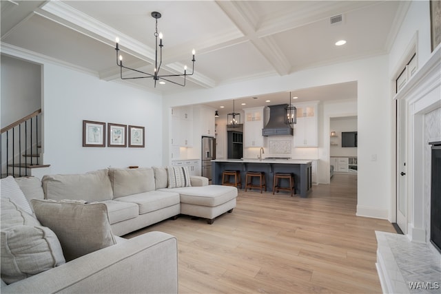 living room with coffered ceiling, crown molding, beam ceiling, light hardwood / wood-style flooring, and a notable chandelier