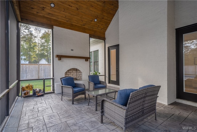 sunroom with an outdoor brick fireplace, lofted ceiling, and wood ceiling