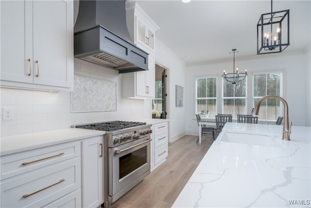 kitchen featuring custom exhaust hood, high end stove, sink, light hardwood / wood-style floors, and white cabinetry